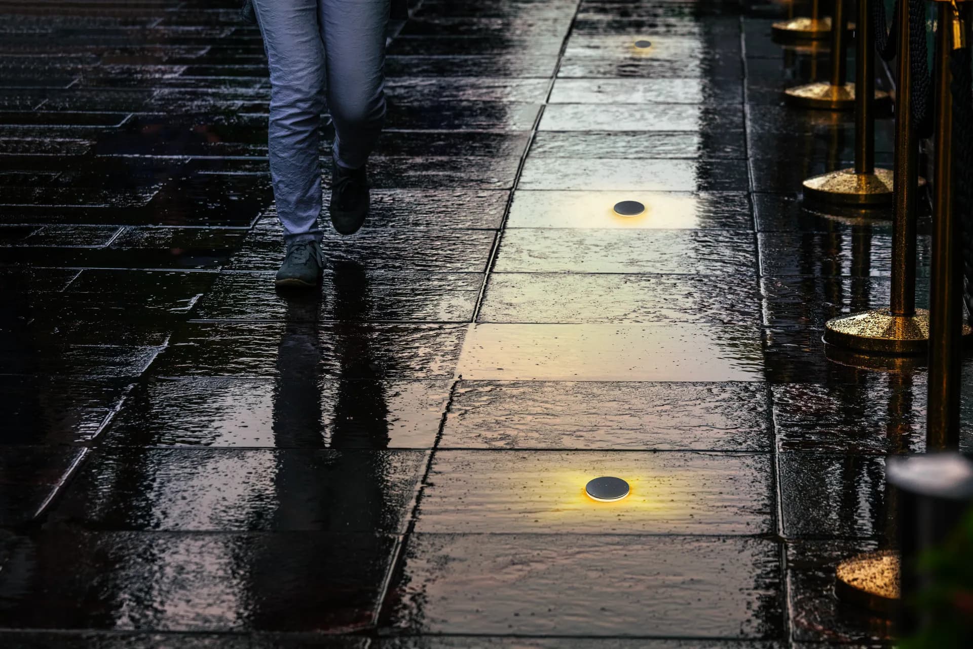 In-ground markers glowing through wet pavement on a rainy night
