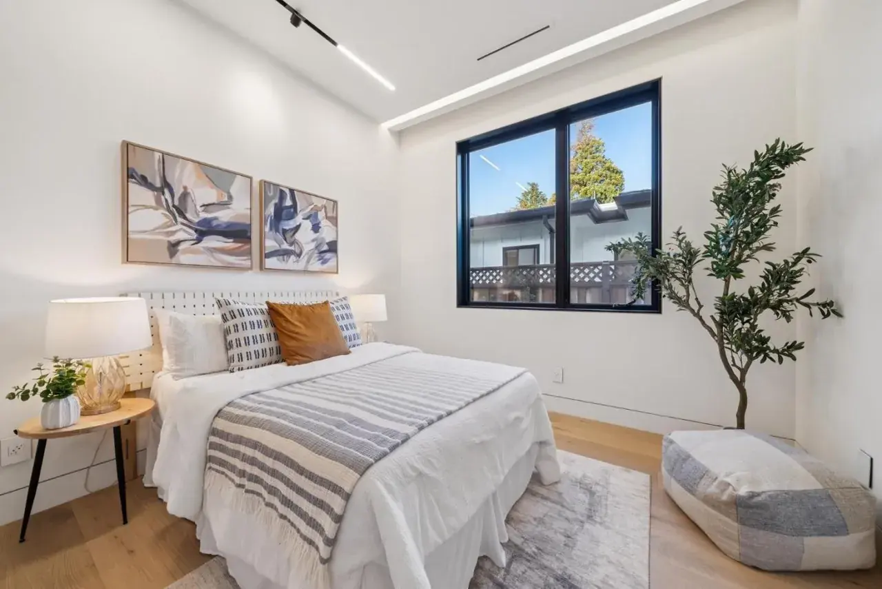 Bedroom with a tall window and a planted corner