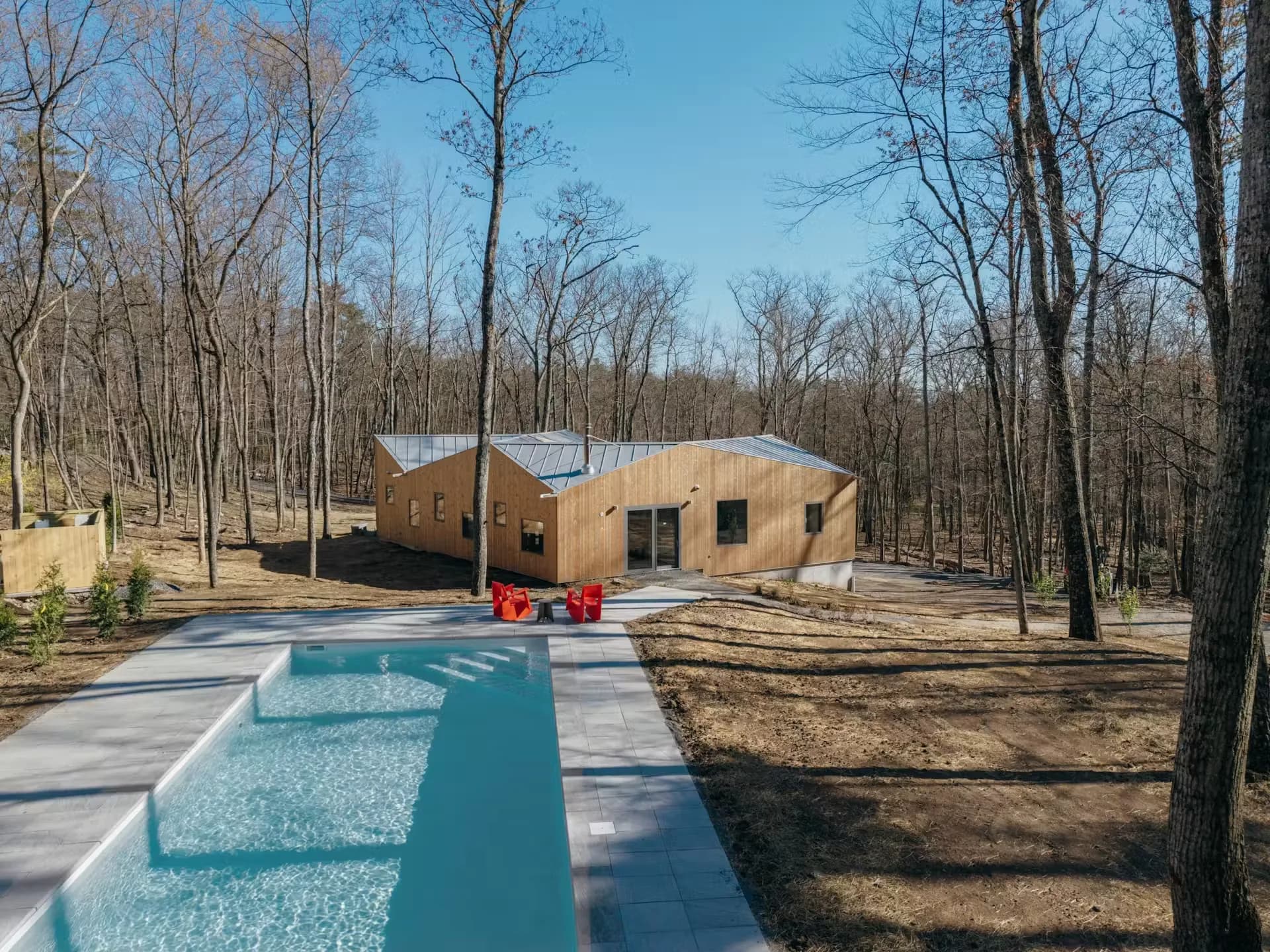 The house seen across a lap pool with winter woods behind