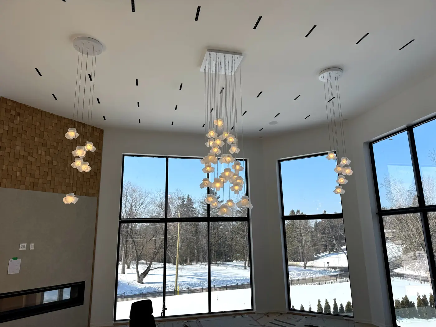 Great room with cascading globe chandeliers against full height glazing