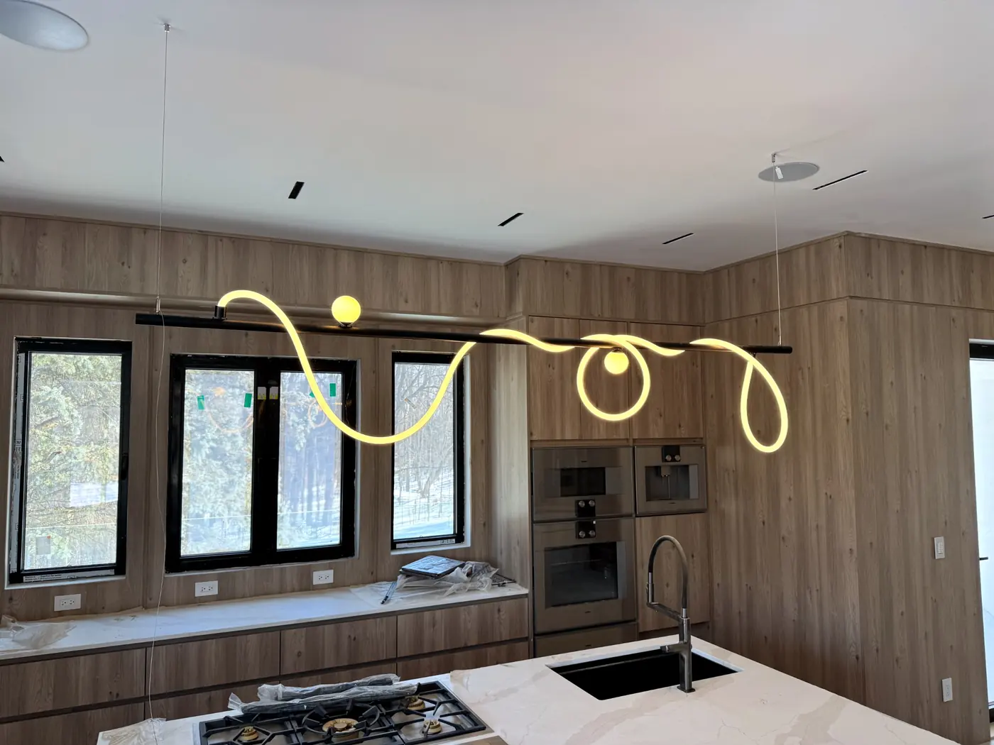 Kitchen with a looping light pendant running above the cooktop