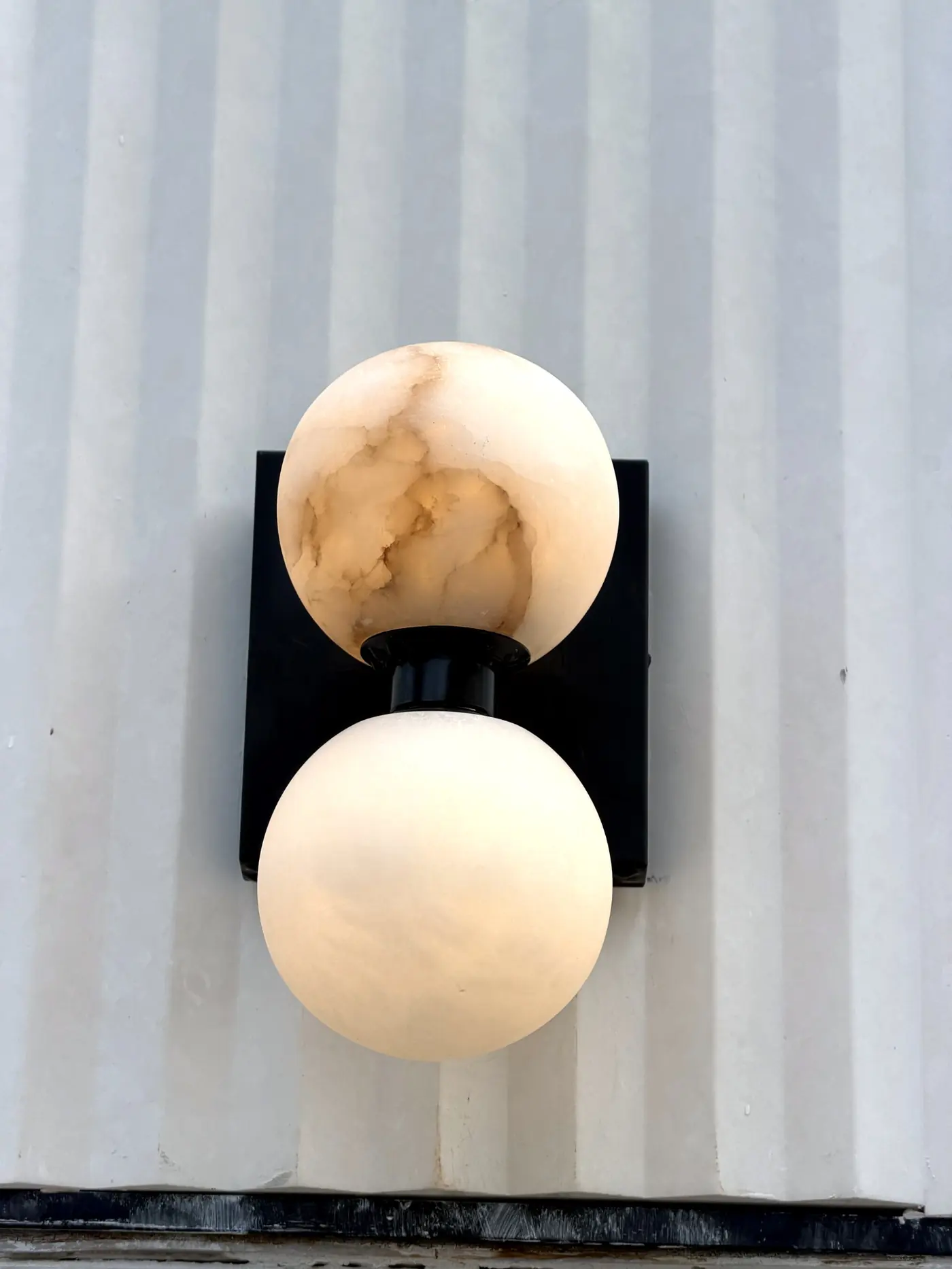 Alabaster globe sconce mounted on a fluted stone wall