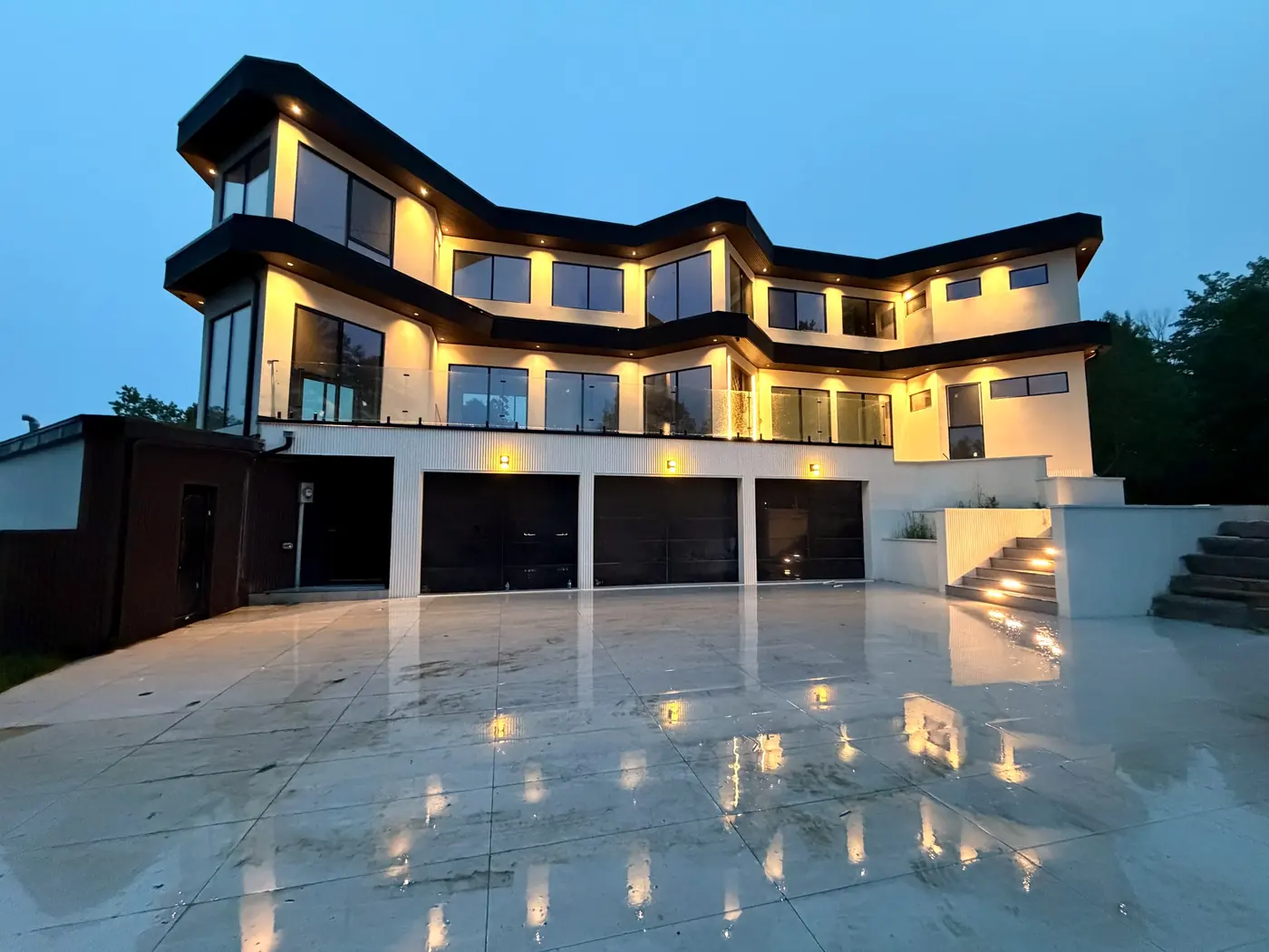 Curved facade at dusk seen across the lit driveway