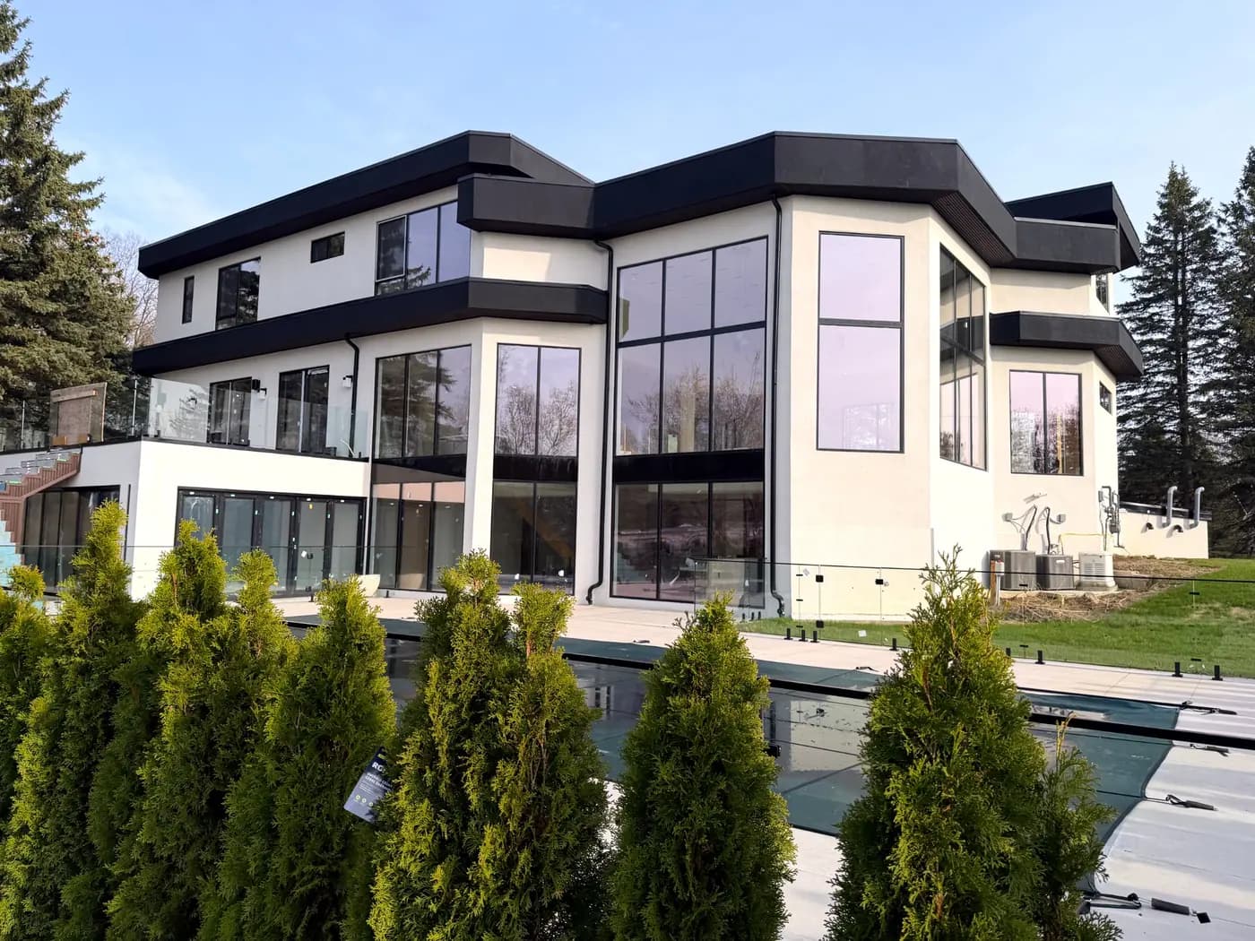 House and pool in daylight behind a clipped hedge