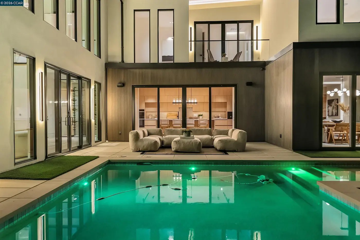 Courtyard pool at night with the surrounding rooms lit behind the glazing