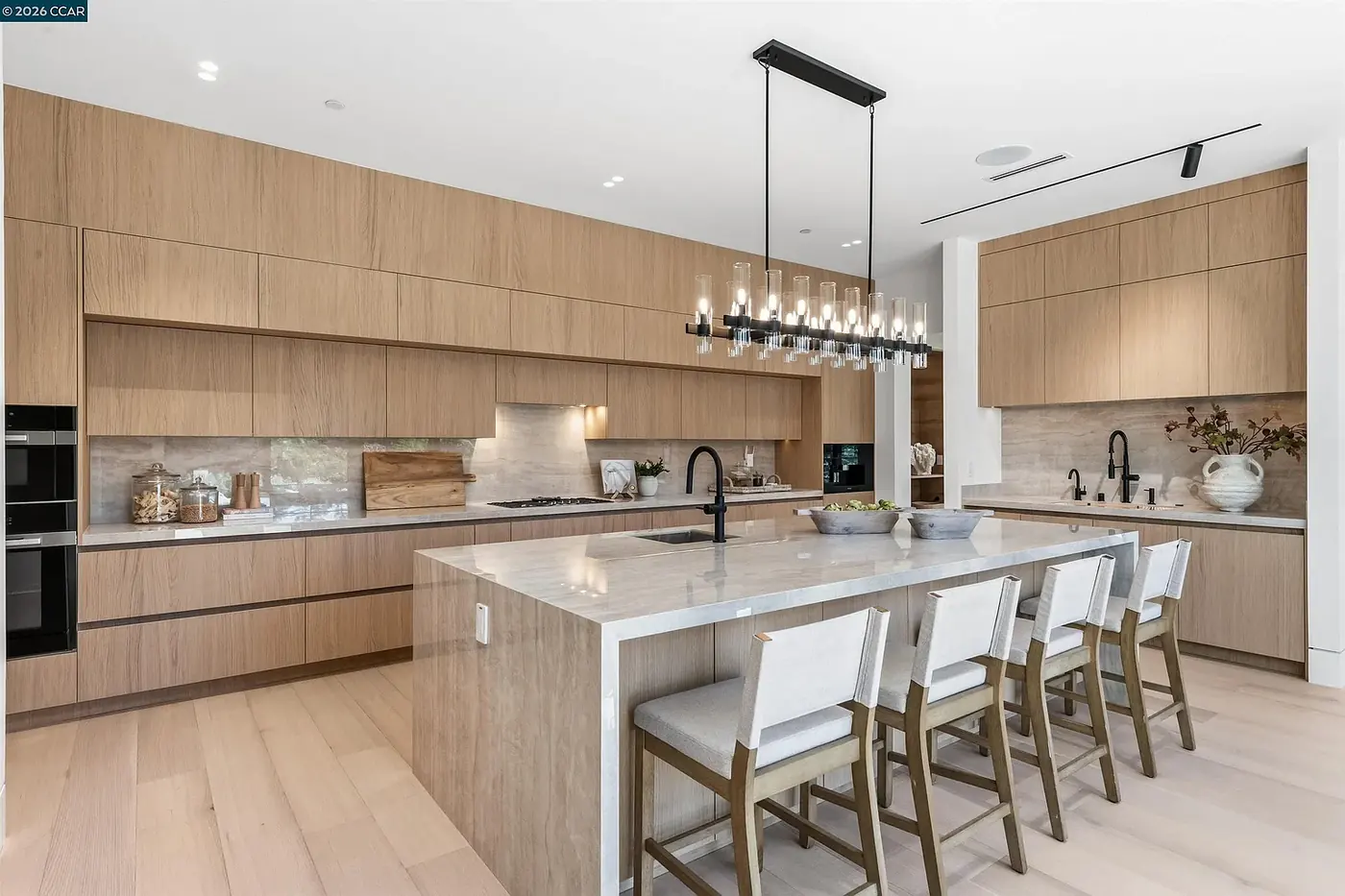 Kitchen island and bar seating under a linear pendant