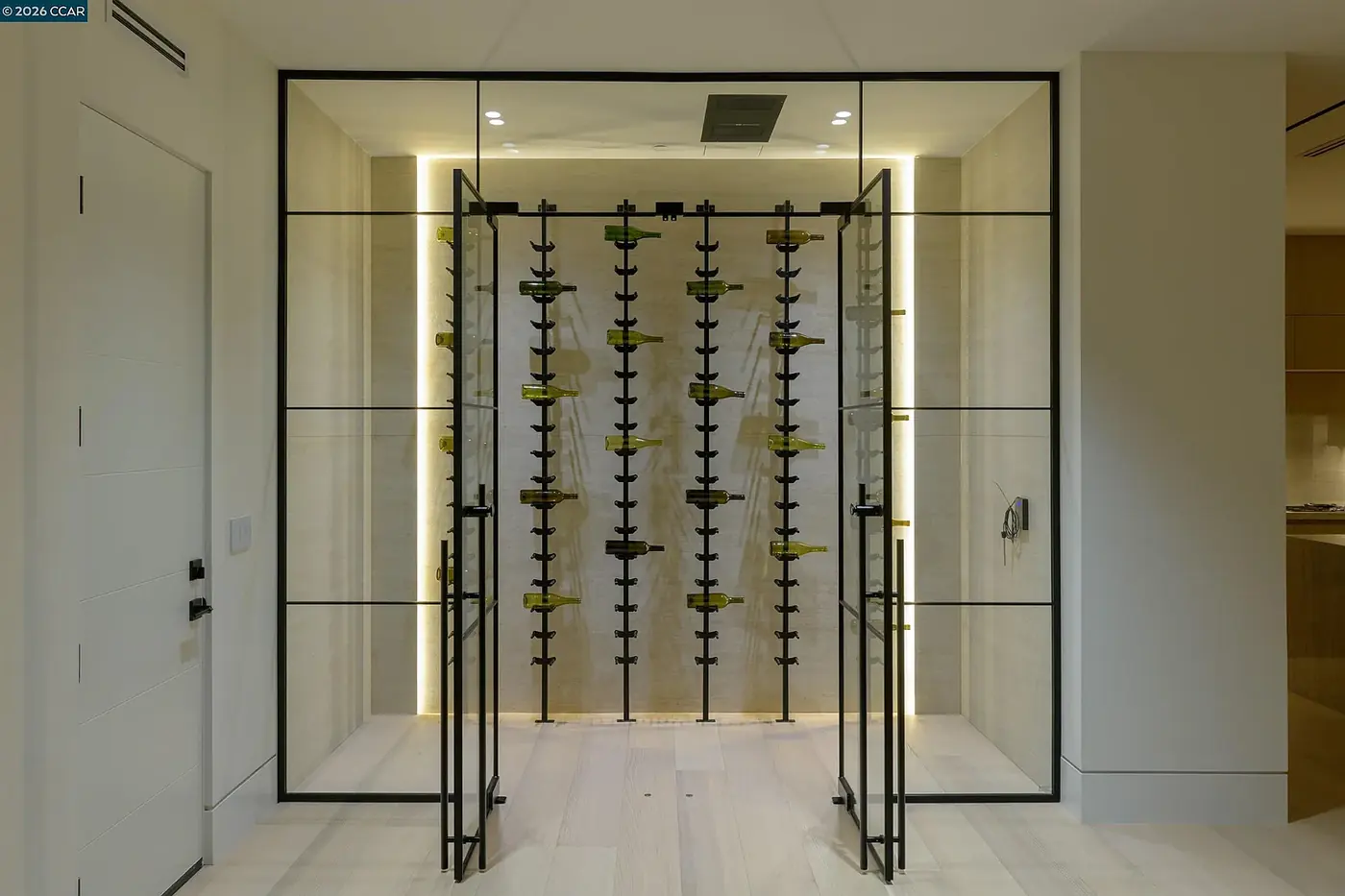Glazed wine room with the rear wall washed in warm light behind the racking