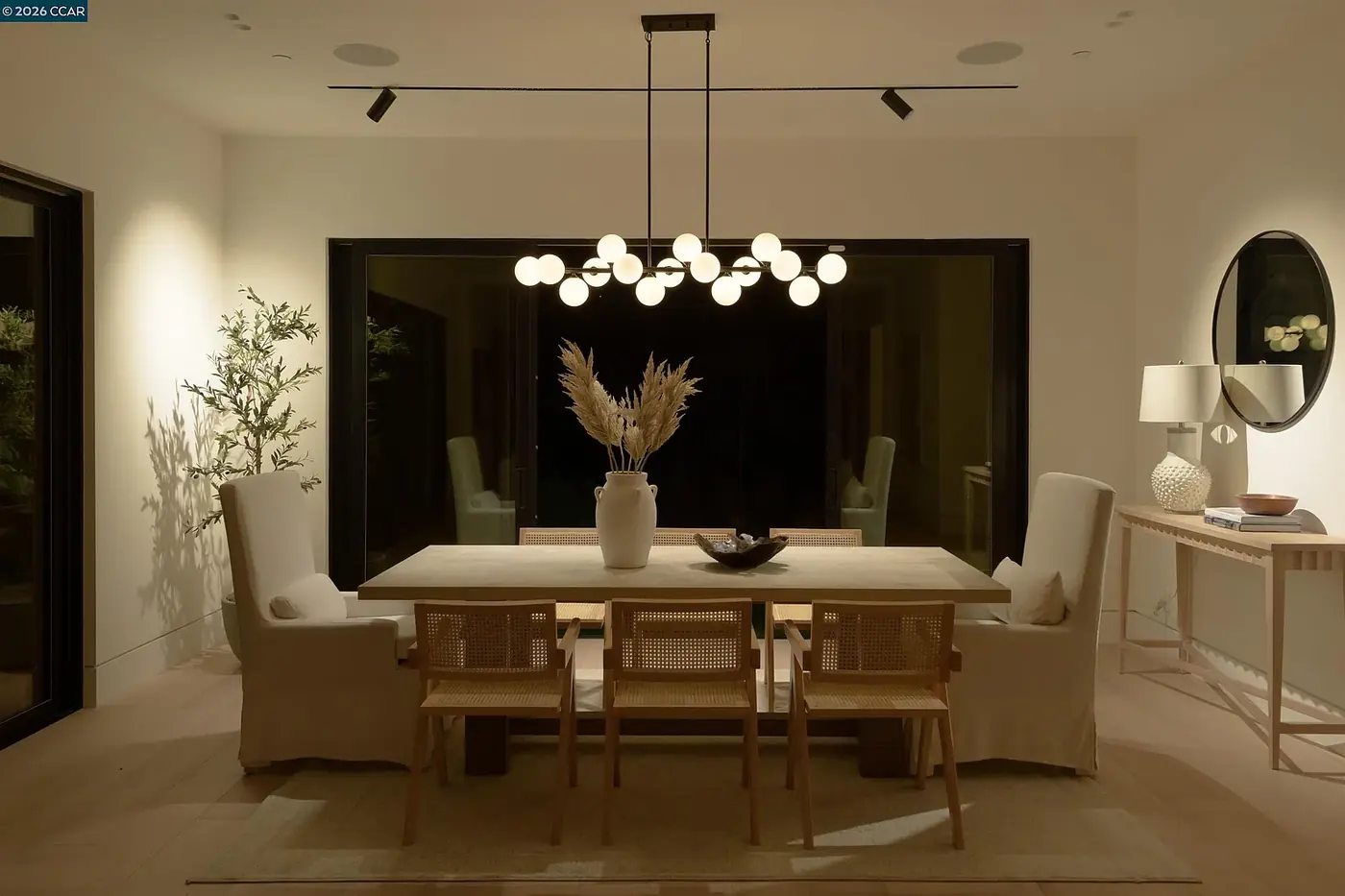 Dining room lit by a globe chandelier with spots washing the walls