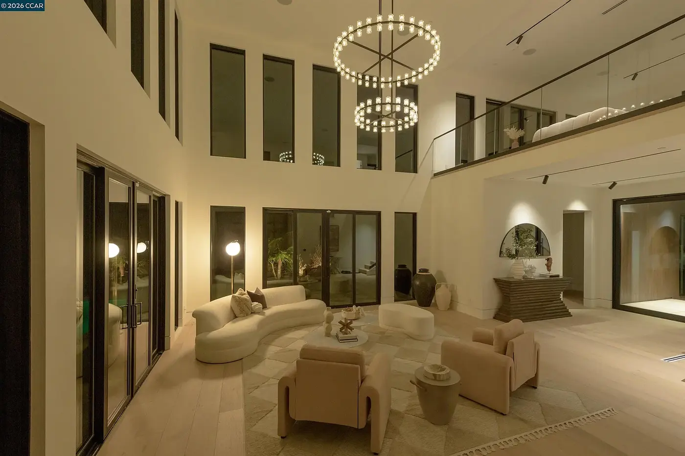Double height living space with a ring chandelier against tall windows