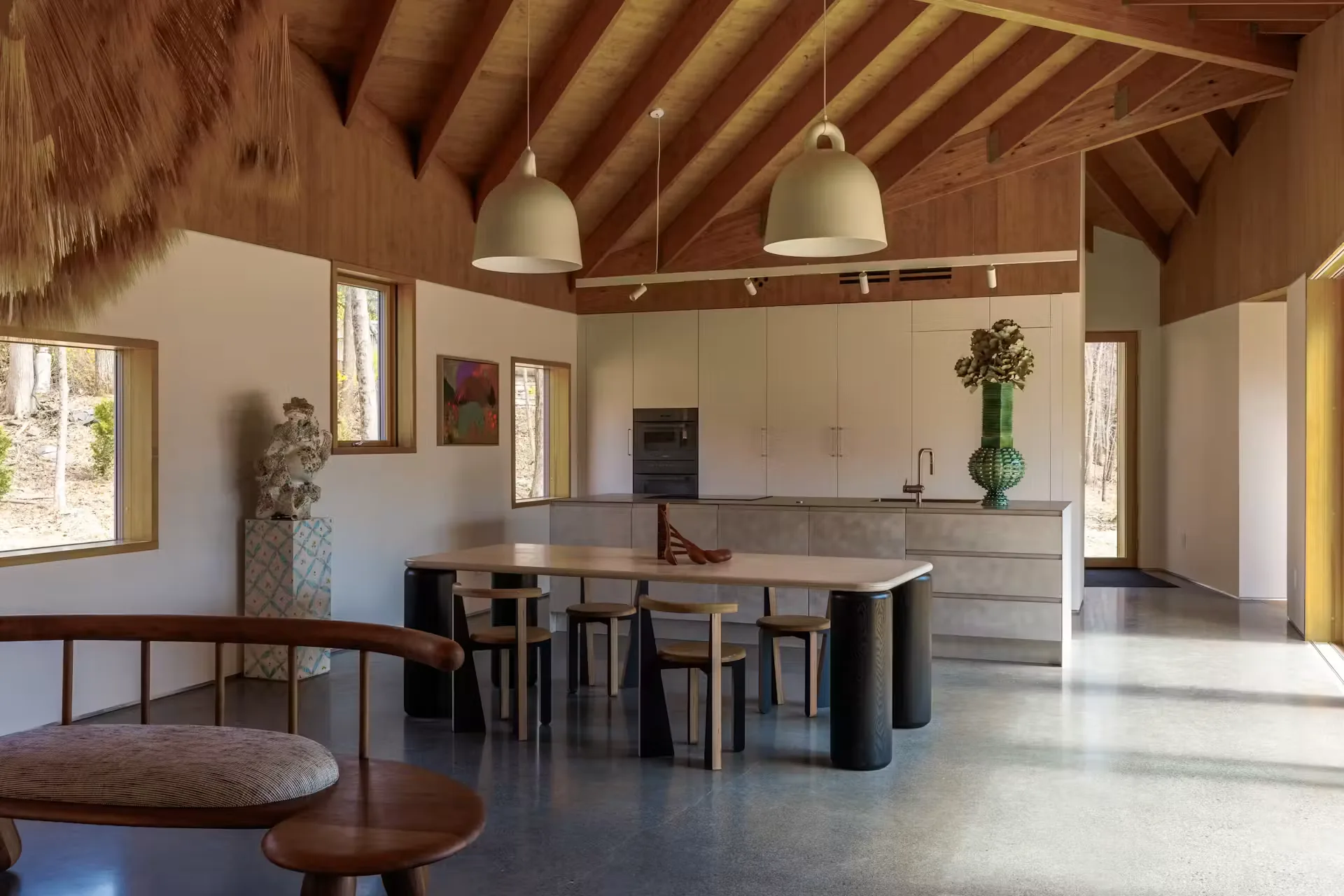 Kitchen and dining under exposed timber rafters, two large pendants over a long table